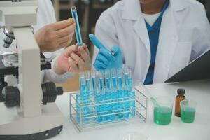 Scientist or medical in lab coat working in biotechnological laboratory, Microscope equipment for research with mixing reagents in glass flask in clinical laboratory. photo