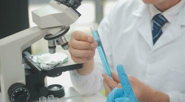 Scientist or medical in lab coat working in biotechnological laboratory, Microscope equipment for research with mixing reagents in glass flask in clinical laboratory. photo