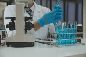 Scientist or medical in lab coat working in biotechnological laboratory, Microscope equipment for research with mixing reagents in glass flask in clinical laboratory. photo