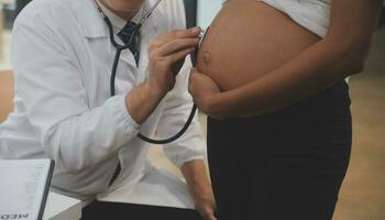 Female doctor is checking pregnant woman with stethoscope. Concept caring for pregnant woman photo