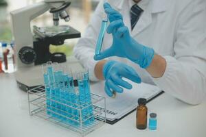 Scientist or medical in lab coat working in biotechnological laboratory, Microscope equipment for research with mixing reagents in glass flask in clinical laboratory. photo