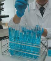 Scientist or medical in lab coat working in biotechnological laboratory, Microscope equipment for research with mixing reagents in glass flask in clinical laboratory. photo