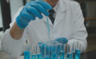 Scientist or medical in lab coat working in biotechnological laboratory, Microscope equipment for research with mixing reagents in glass flask in clinical laboratory. photo