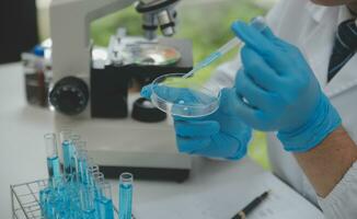 Scientist or medical in lab coat working in biotechnological laboratory, Microscope equipment for research with mixing reagents in glass flask in clinical laboratory. photo