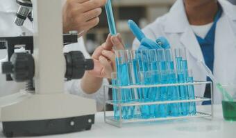 Scientist or medical in lab coat working in biotechnological laboratory, Microscope equipment for research with mixing reagents in glass flask in clinical laboratory. photo