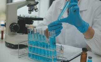 Scientist or medical in lab coat working in biotechnological laboratory, Microscope equipment for research with mixing reagents in glass flask in clinical laboratory. photo
