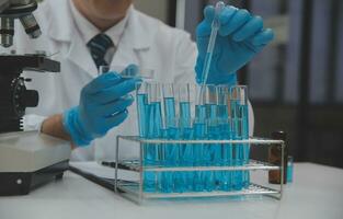 Scientist or medical in lab coat working in biotechnological laboratory, Microscope equipment for research with mixing reagents in glass flask in clinical laboratory. photo