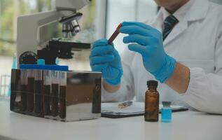 Scientist or medical in lab coat working in biotechnological laboratory, Microscope equipment for research with mixing reagents in glass flask in clinical laboratory. photo