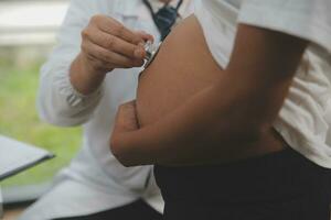 Female doctor is checking pregnant woman with stethoscope. Concept caring for pregnant woman photo