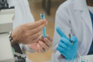 Scientist or medical in lab coat working in biotechnological laboratory, Microscope equipment for research with mixing reagents in glass flask in clinical laboratory. photo