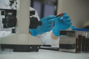 Scientist or medical in lab coat working in biotechnological laboratory, Microscope equipment for research with mixing reagents in glass flask in clinical laboratory. photo