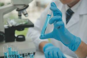 Scientist or medical in lab coat working in biotechnological laboratory, Microscope equipment for research with mixing reagents in glass flask in clinical laboratory. photo