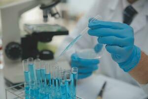 Scientist or medical in lab coat working in biotechnological laboratory, Microscope equipment for research with mixing reagents in glass flask in clinical laboratory. photo