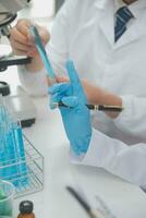 Scientist or medical in lab coat working in biotechnological laboratory, Microscope equipment for research with mixing reagents in glass flask in clinical laboratory. photo