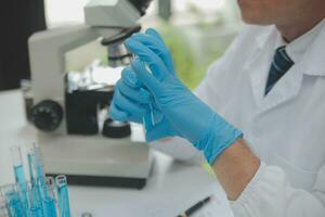 Scientist or medical in lab coat working in biotechnological laboratory, Microscope equipment for research with mixing reagents in glass flask in clinical laboratory. photo