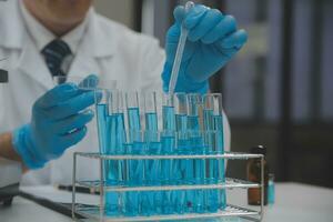 Scientist or medical in lab coat working in biotechnological laboratory, Microscope equipment for research with mixing reagents in glass flask in clinical laboratory. photo