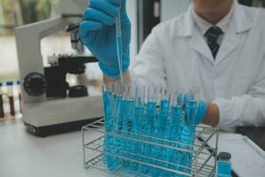 Scientist or medical in lab coat working in biotechnological laboratory, Microscope equipment for research with mixing reagents in glass flask in clinical laboratory. photo