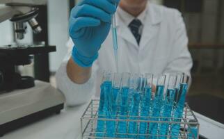 Scientist or medical in lab coat working in biotechnological laboratory, Microscope equipment for research with mixing reagents in glass flask in clinical laboratory. photo