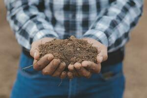 Male hands touching soil on the field. Expert hand of farmer checking soil health before growth a seed of vegetable or plant seedling. Business or ecology concept. photo