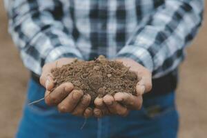 Male hands touching soil on the field. Expert hand of farmer checking soil health before growth a seed of vegetable or plant seedling. Business or ecology concept. photo