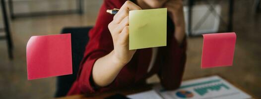 mujer de negocios asiática que usa una computadora portátil y trabaja en la oficina con un documento de calculadora en el escritorio, planificando el análisis del informe financiero, la inversión del plan de negocios, el concepto de análisis financiero. foto