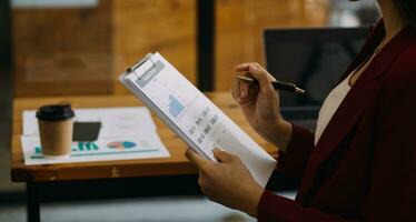 Asian Businesswoman Using laptop computer and working at office with calculator document on desk, doing planning analyzing the financial report, business plan investment, finance analysis concept. photo