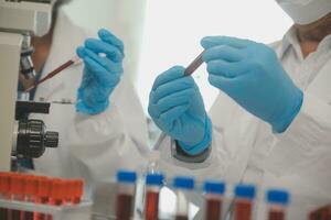 investigadores de atención médica que trabajan en el laboratorio de ciencias de la vida. joven científica investigadora y supervisora masculina senior preparando y analizando portaobjetos de microscopio en el laboratorio de investigación. foto