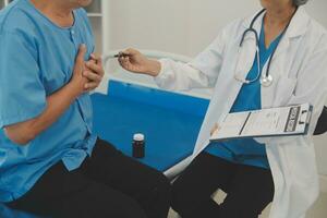 Close up of Female Doctor using stethoscope putting beat heart diagnose with patient in examination room at a hospital, check-up body, Medical and Health Care Concept. photo