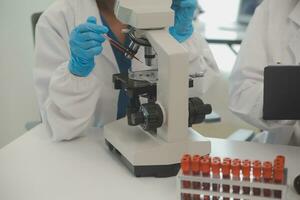 investigadores de atención médica que trabajan en el laboratorio de ciencias de la vida. joven científica investigadora y supervisora masculina senior preparando y analizando portaobjetos de microscopio en el laboratorio de investigación. foto