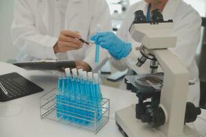 Health care researchers working in life science laboratory. Young female research scientist and senior male supervisor preparing and analyzing microscope slides in research lab. photo