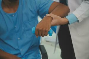 fisioterapeuta hombre dando ejercicio con pesa tratamiento acerca de brazo y hombro de atleta masculino paciente físico terapia concepto foto