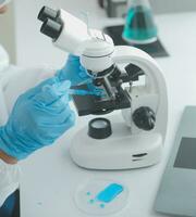 Health care researchers working in life science laboratory. Young female research scientist and senior male supervisor preparing and analyzing microscope slides in research lab. photo