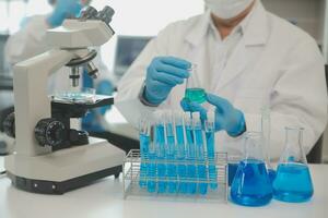 Health care researchers working in life science laboratory. Young female research scientist and senior male supervisor preparing and analyzing microscope slides in research lab. photo