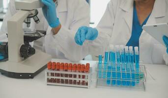 investigadores de atención médica que trabajan en el laboratorio de ciencias de la vida. joven científica investigadora y supervisora masculina senior preparando y analizando portaobjetos de microscopio en el laboratorio de investigación. foto