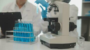 Health care researchers working in life science laboratory. Young female research scientist and senior male supervisor preparing and analyzing microscope slides in research lab. photo