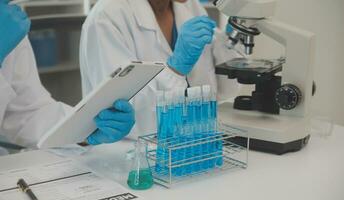 Health care researchers working in life science laboratory. Young female research scientist and senior male supervisor preparing and analyzing microscope slides in research lab. photo