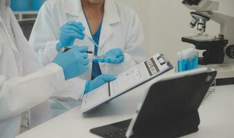 Health care researchers working in life science laboratory. Young female research scientist and senior male supervisor preparing and analyzing microscope slides in research lab. photo