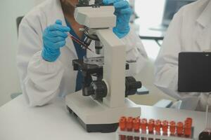 Health care researchers working in life science laboratory. Young female research scientist and senior male supervisor preparing and analyzing microscope slides in research lab. photo