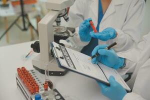 investigadores de atención médica que trabajan en el laboratorio de ciencias de la vida. joven científica investigadora y supervisora masculina senior preparando y analizando portaobjetos de microscopio en el laboratorio de investigación. foto