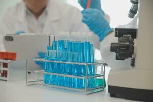 Health care researchers working in life science laboratory. Young female research scientist and senior male supervisor preparing and analyzing microscope slides in research lab. photo