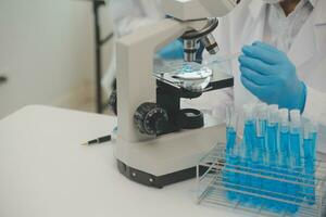 Health care researchers working in life science laboratory. Young female research scientist and senior male supervisor preparing and analyzing microscope slides in research lab. photo