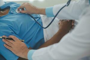 Close up of doctor sitting on bedside of male patient in hospital photo