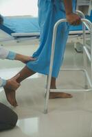 young asian physical therapist working with senior woman on walking with a walker photo