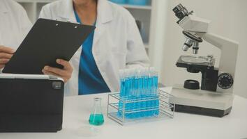 Health care researchers working in life science laboratory. Young female research scientist and senior male supervisor preparing and analyzing microscope slides in research lab. photo