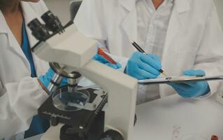 Health care researchers working in life science laboratory. Young female research scientist and senior male supervisor preparing and analyzing microscope slides in research lab. photo
