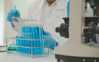 Health care researchers working in life science laboratory. Young female research scientist and senior male supervisor preparing and analyzing microscope slides in research lab. photo