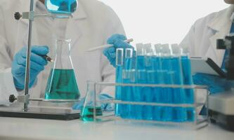 Health care researchers working in life science laboratory. Young female research scientist and senior male supervisor preparing and analyzing microscope slides in research lab. photo