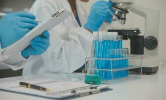 Health care researchers working in life science laboratory. Young female research scientist and senior male supervisor preparing and analyzing microscope slides in research lab. photo