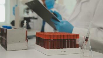 Health care researchers working in life science laboratory. Young female research scientist and senior male supervisor preparing and analyzing microscope slides in research lab. photo