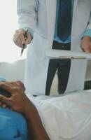 Close up of doctor sitting on bedside of male patient in hospital photo